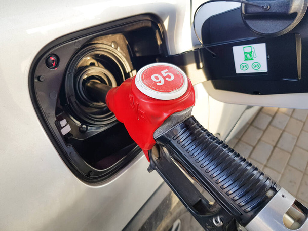 ガソリンで車を満たす。給油のために車のタンクに赤い銃を挿入します。燃料で車を給油するプロセス - 写真・画像