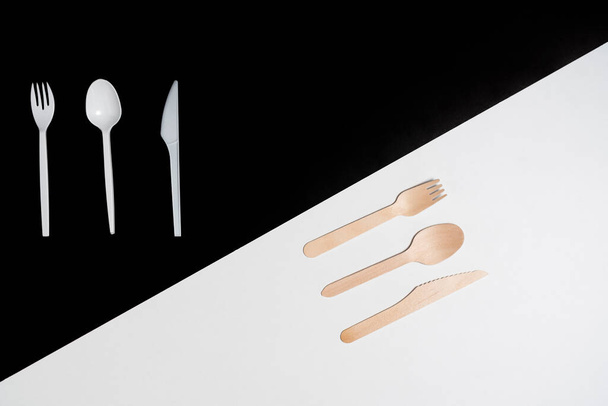 Utensilios de cocina cuchara, tenedor, cuchillo, madera vs plástico se muestra a través del concepto de materiales plásticos y sus características nocivas en relación con los de los materiales naturales. - Foto, imagen