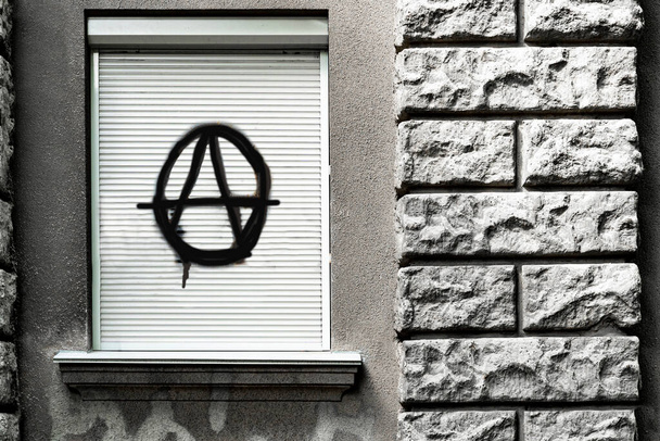 black sign of anarchy on the closed window. culture of anarchists, punks, and street protests. Symbol of Anarchy painted on a window - Photo, Image