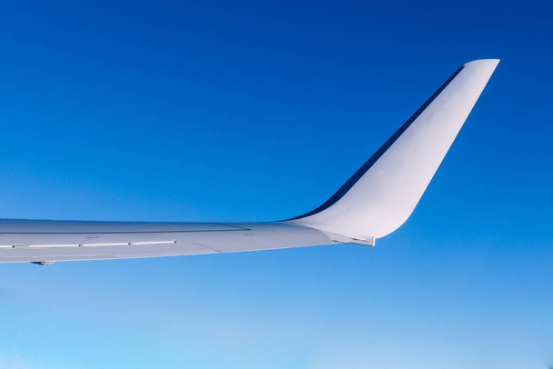 Πτέρυγα αεροπλάνου που πετάει πάνω από τα σύννεφα. Οι άνθρωποι κοιτάζουν τον ουρανό από το παράθυρο του αεροπλάνου, χρησιμοποιώντας τις αερομεταφορές για να ταξιδέψουν. - Φωτογραφία, εικόνα