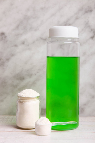 Montón de polvo de proteína blanca con cuchara dosificadora y botella sobre fondo de mármol. - Foto, imagen