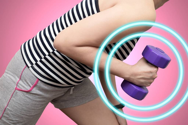 紫のダンベルを持ち上げることで運動をするアジアの女性。トリップに取り組んでる。ピンクの背景とダンベルの円の波で隔離された. - 写真・画像