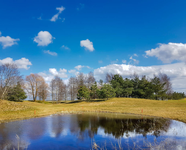 Sunny spring landscape with small lakes on flooded meadows on the banks of Kisezers in Riga, Latvia.White cumulus clouds are reflected in the water. - Foto, imagen