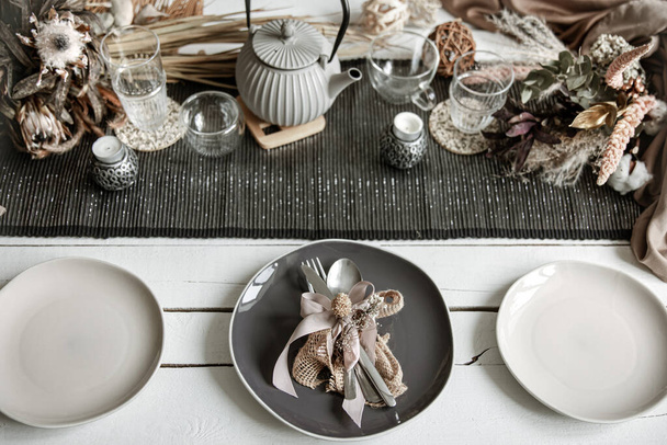 Stilvolles Geschirr und Besteck auf einem gedeckten Tisch in Kaffeefarben mit dekorativen Elementen im skandinavischen Stil. - Foto, Bild
