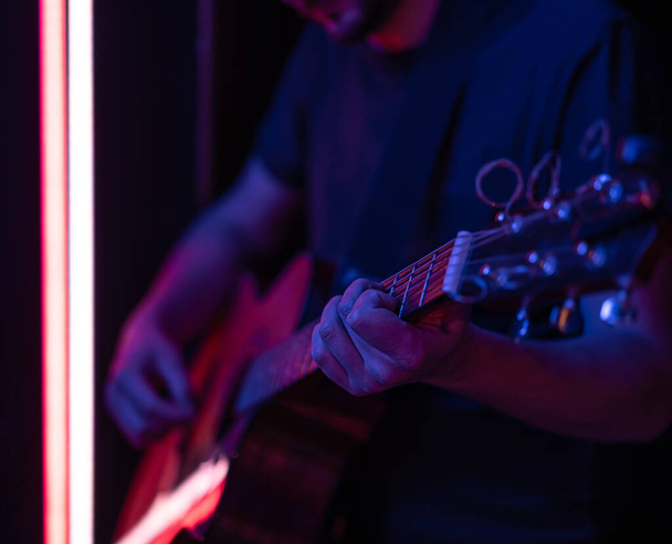 Un homme joue de la guitare acoustique dans une pièce sombre. Spectacle live, concert acoustique. - Photo, image