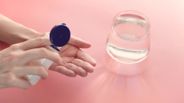 Vitamines de couleur jaune dans une main sur un fond rose. Derrière - un verre d'eau. Le concept de prise de vitamines, compléments alimentaires, promotion de la santé. - Séquence, vidéo