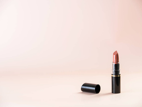 Open lipstick with a cap lying next to it on a powdery background. Side view. - Foto, imagen