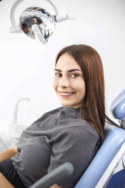 Onnellinen nuori nainen potilas istuu gynekologin tai hammaslääkärin lääketieteellisessä tuolissa. - Valokuva, kuva