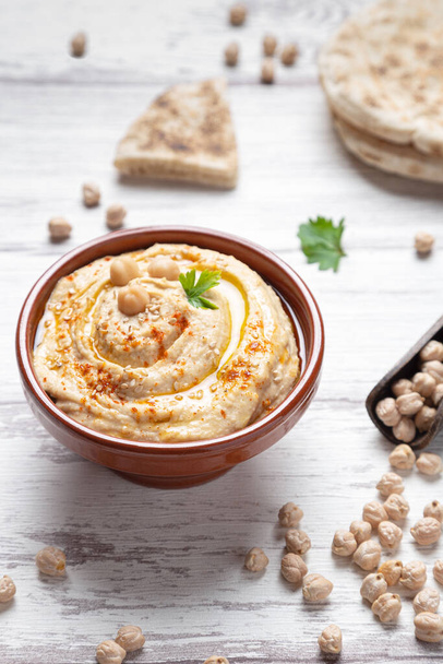Bowl of homemade hummus on light background vertical format. - Photo, image