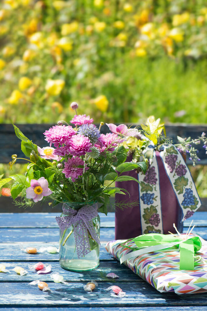 Regalo con mazzo di fiori selvatici su un tavolo da giardino - Foto, immagini