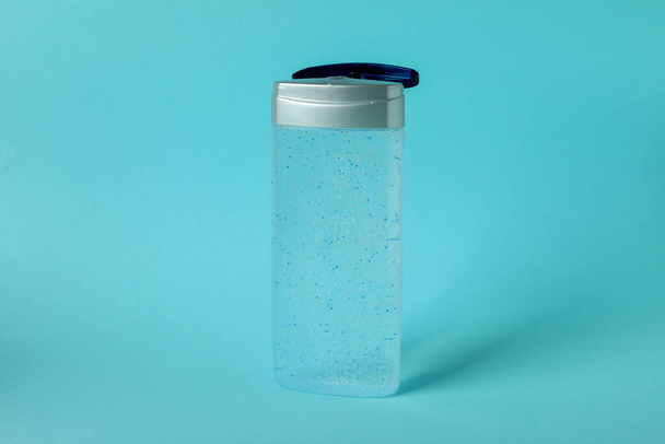 Порожня пляшка гелю для душу на синьому фоні
 - Фото, зображення