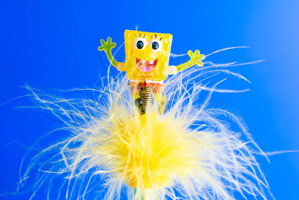 fairy-tale yellow smiling creature in feathers on a blue background - Photo, Image