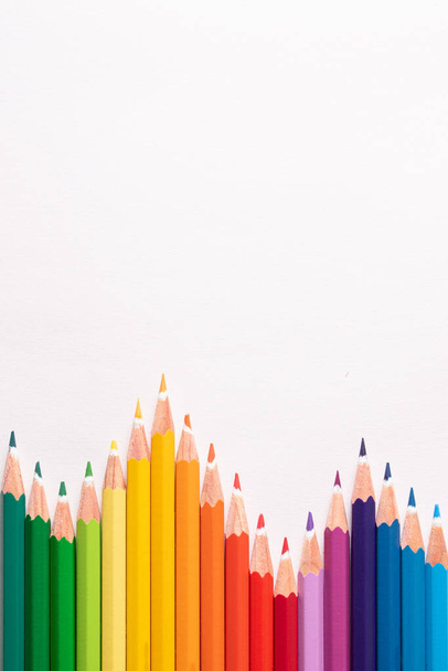 Στο πάνω μέρος. Χρωματιστά μολύβια το ένα δίπλα στο άλλο σε σχήμα ιστόγραμμα ή βουνού σε λευκό φόντο και προς τα πάνω. Αντιγραφή χώρου. - Φωτογραφία, εικόνα