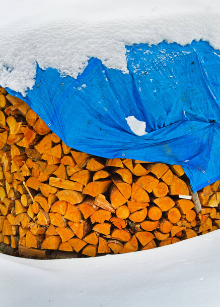 Το απόθεμα καυσόξυλων για το χειμώνα καλύπτεται με μπλε τέντα - Φωτογραφία, εικόνα