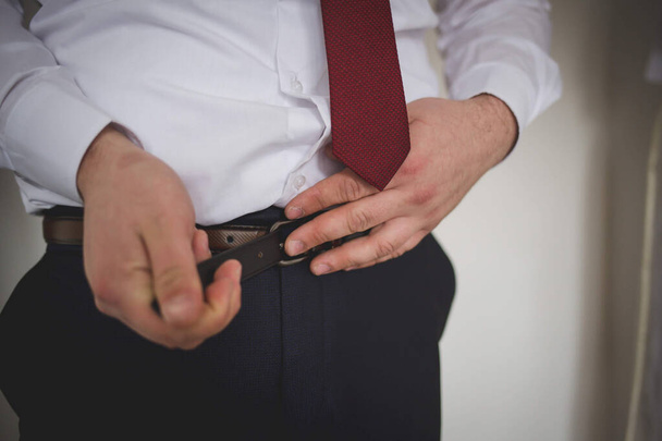 A closeup shot of a man tightening his belt - Foto, afbeelding