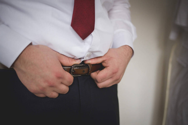 A closeup shot of a man tightening his belt - Foto, Bild