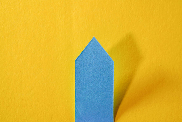 An isolated shot of a blue arrow on a yellow background - Zdjęcie, obraz