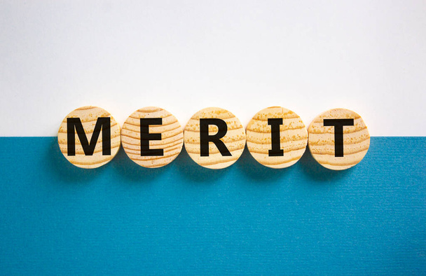 Merit symbol. Wooden circles with the word 'merit'. Beautiful white and blue background, copy space. Business and merit concept. - Foto, immagini