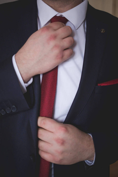 A vertical shot of a man wearing an elegant suit with a red tie - Фото, изображение