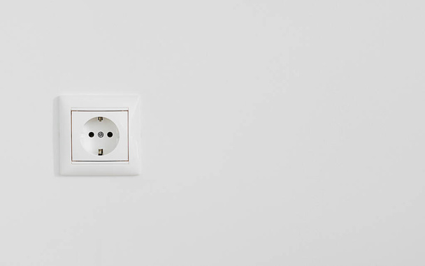 Toma de corriente eléctrica blanca en pared enlucida blanca, primer plano con espacio de copia - Foto, Imagen