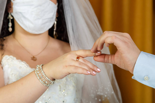 Groom putting the ring on the forefinger on the forefinger at the Jewish wedding hand close-up of a bride in a mask. Horizontal photo - Zdjęcie, obraz