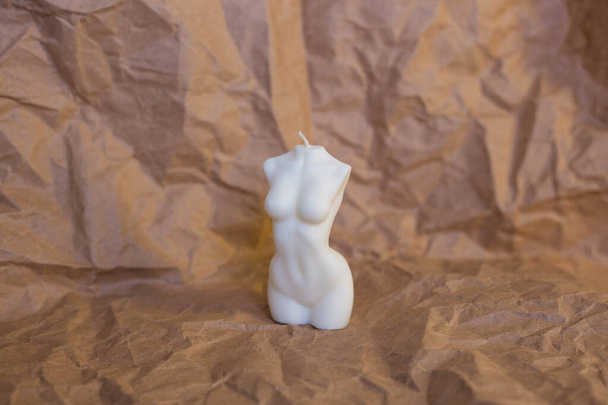 White candle in the form of a female figure on a paper background - Fotografie, Obrázek