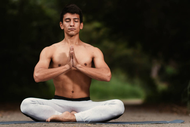 Молодой латиноамериканец медитирует и практикует йогу в лесу - Фото, изображение