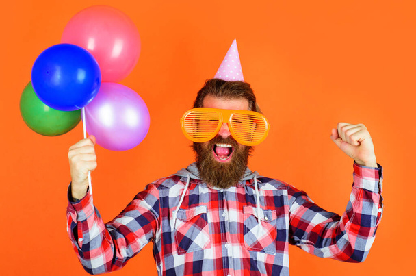 Partyzeit. Freude, Spaß und Glück Konzept. Glücklicher Mann mit Luftballons. Bärtiger Mann mit Partymütze und großer Brille. - Foto, Bild