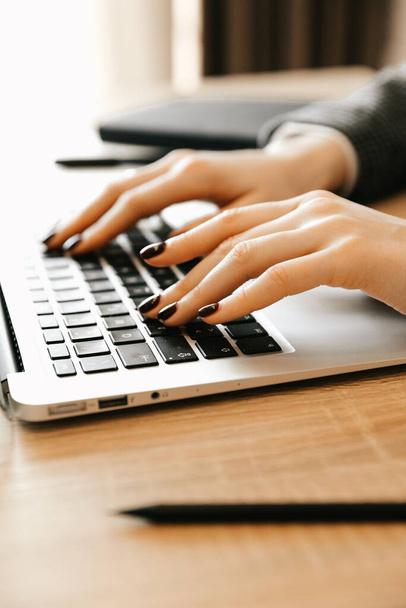 Kobieta pracująca w biurze, z zamkniętymi rękami na klawiaturze. Kobieta pracująca w domu z laptopem pisze bloga. Kobiece dłonie na klawiaturze - Zdjęcie, obraz