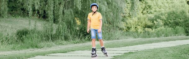 Feliz niño preadolescente caucásico sonriente en el casco de montar patines sobre ruedas en la carretera en el parque en el día de verano. Deporte de actividad infantil estacional al aire libre. Estilo de vida saludable de la infancia. Encabezado del banner web. - Foto, imagen