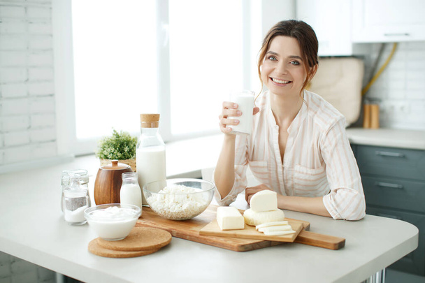 The woman is drinking milk in her kitchen. - Fotó, kép