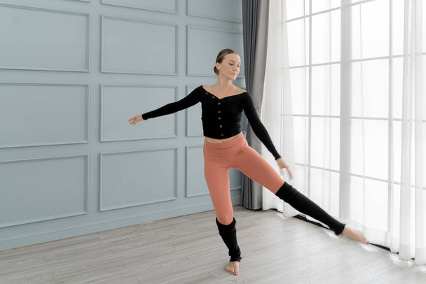 portrait of woman ballet dancer perform in studio house. Contemporary dance performer. Classical Ballet dancer training. Beautiful graceful ballerina practice ballet at wall and window light hall. - Photo, Image