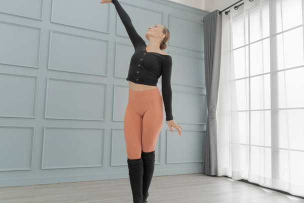 portrait of woman ballet dancer perform in studio house. Contemporary dance performer. Classical Ballet dancer training. Beautiful graceful ballerina practice ballet at wall and window light hall. - Photo, Image