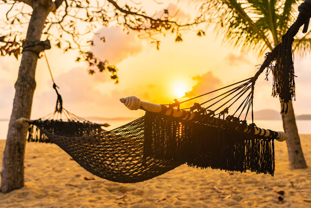 hamaca vacía oscilación alrededor del océano del mar de la playa en la puesta del sol o la hora del amanecer para las vacaciones del recorrido del ocio - Foto, Imagen