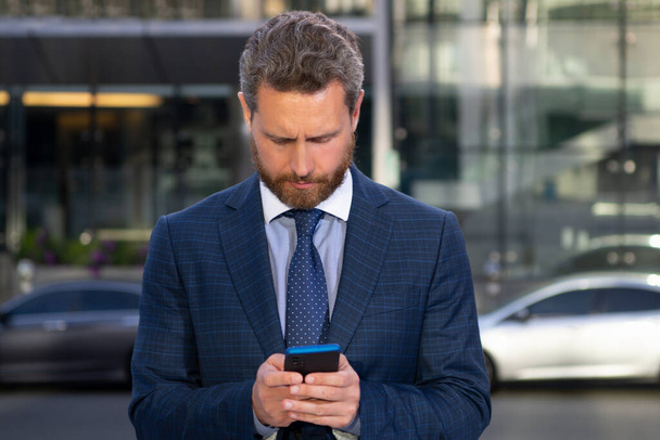 Business man texting message on smartphone near office. - Фото, изображение
