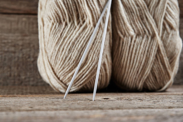 Dos madejas de hilo de lana y agujas para tejer sobre un fondo de madera - Foto, imagen