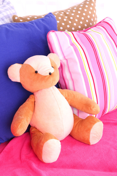 Bear toy with pillows on sofa - Фото, зображення