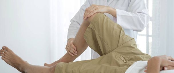 Pacienti mužského pohlaví konzultovali fyzioterapeuty s problémy s bolestí kolena pro vyšetření a léčbu v rehabilitačních centrech. Rehabilitační fyzioterapeutický koncept. - Fotografie, Obrázek
