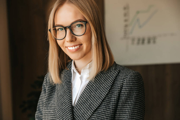 Portrait of a business woman in glasses, in a strict business suit, smiling with teeth in the office. Office successful happy worker. High quality photo - Photo, Image