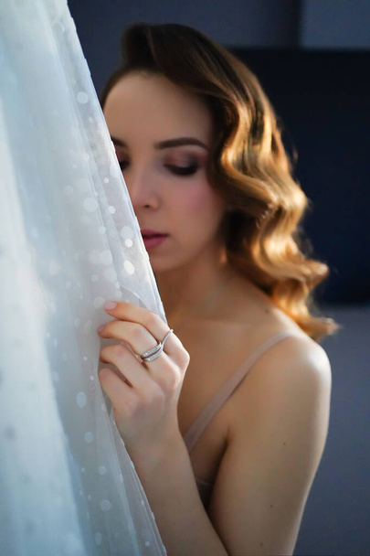 bride with long hair in underwear next to a white wedding dress - Fotoğraf, Görsel