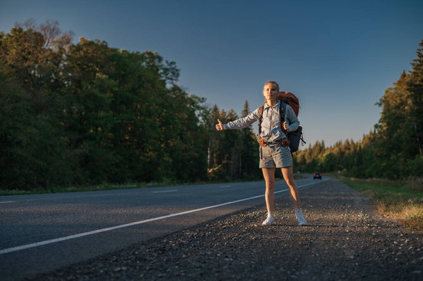 Travel woman with backpack hitchhiking on road - Photo, Image