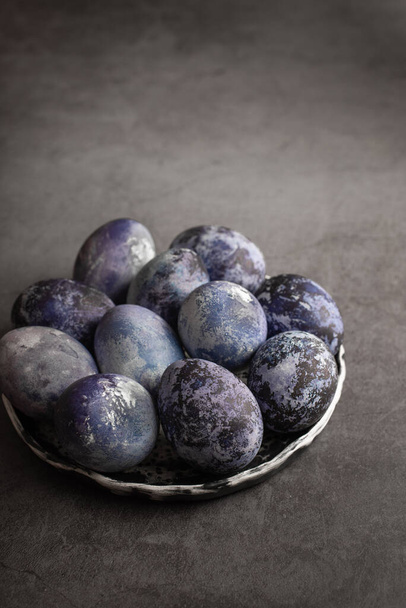 organic Easter eggs close-up, hand-painted with natural blueberries, lie in a clay cup on a stone table. Easter concept. - Φωτογραφία, εικόνα