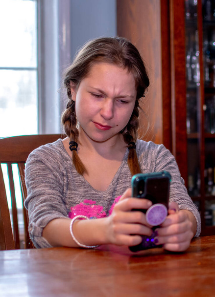 joven chica hace una cara mientras mira un mensaje en su teléfono celular - Foto, imagen