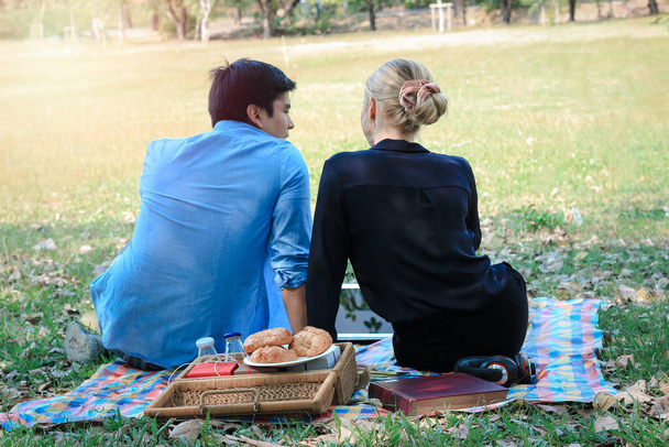 Makea pari rentouttava piknikillä puistossa, nuori kaunis rakastaja viettää aikaa yhdessä ja ottaa romanttinen hetki kesäpuutarhassa, rakkaus ja romanttinen päivämäärä käsite - Valokuva, kuva