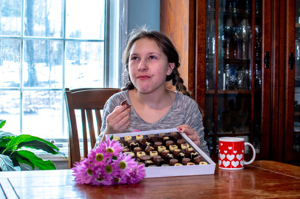 nuori tyttö tekee huonot kasvot, kun hän maistuu epämiellyttävä maku suklaata - Valokuva, kuva