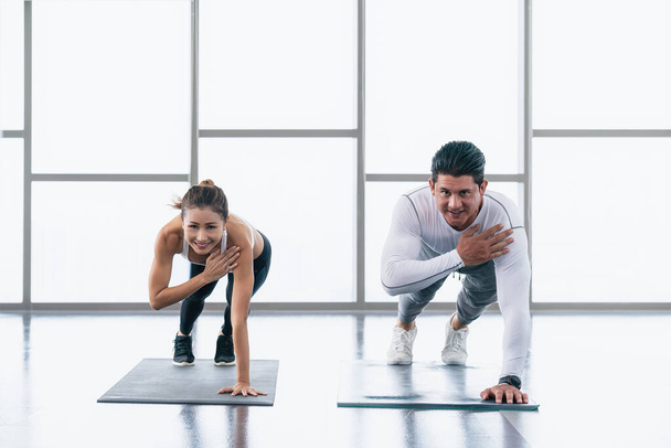 diverse athletic couple Caucasian and Asian in sportswear workout and sport training with push up together in gym and fitness club. Athletics couple healthy and wellness lifestyle - 写真・画像