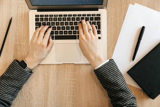 Mujer trabajando en la mesa con un ordenador, escribiendo texto y mirando a través de correo, trabajador de oficina en la mesa, vista superior. Foto de alta calidad - Foto, imagen