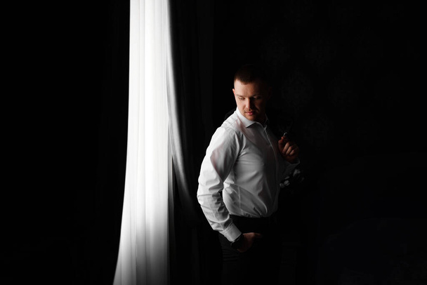 man in a white shirt by the window in a dark room.  - Photo, Image