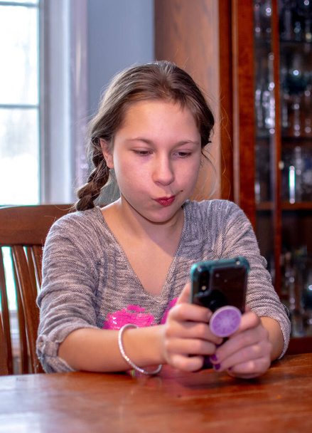 joven adolescente scrolls thru en su celular - Foto, imagen
