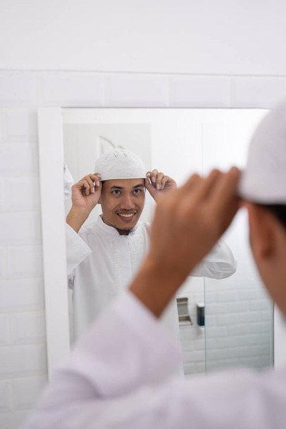 muslim man looking at mirror and get dressed wearing islamic hat or cap - Fotografie, Obrázek